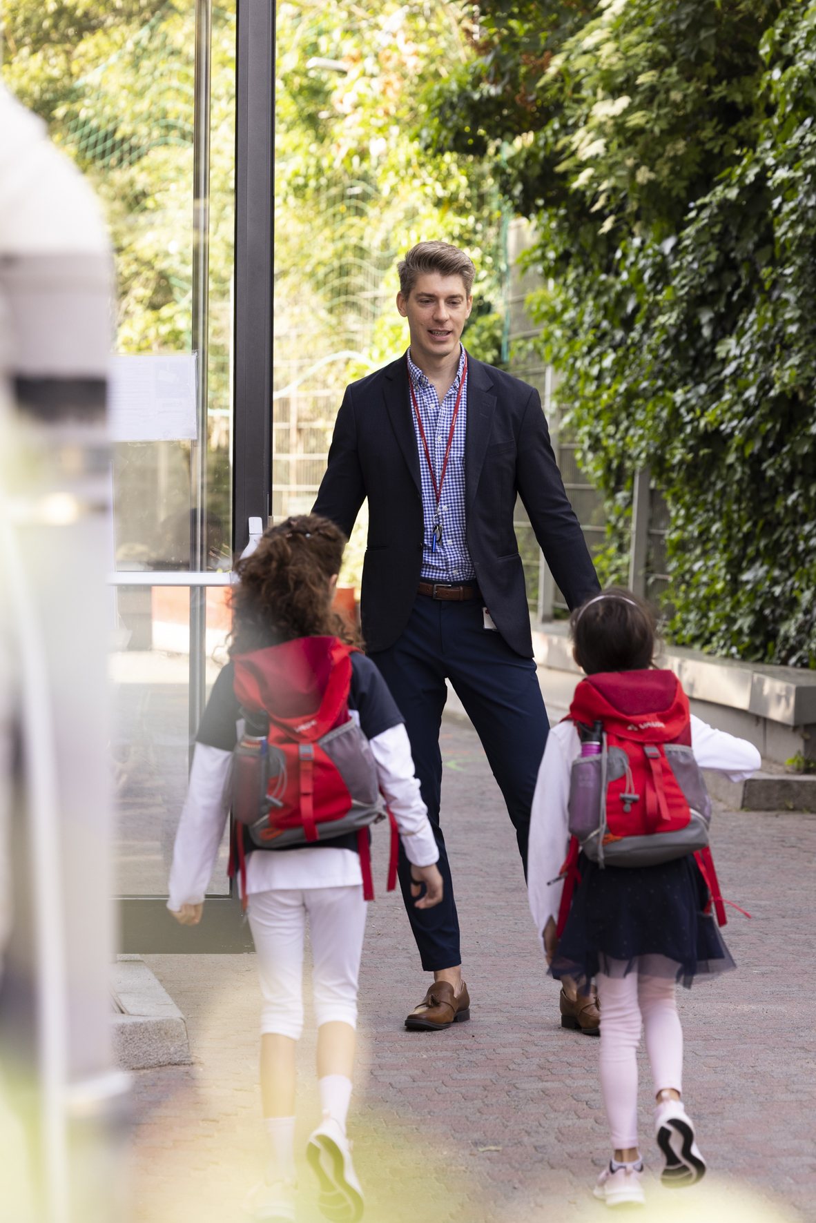 Nick greeting two young students at a school entrance