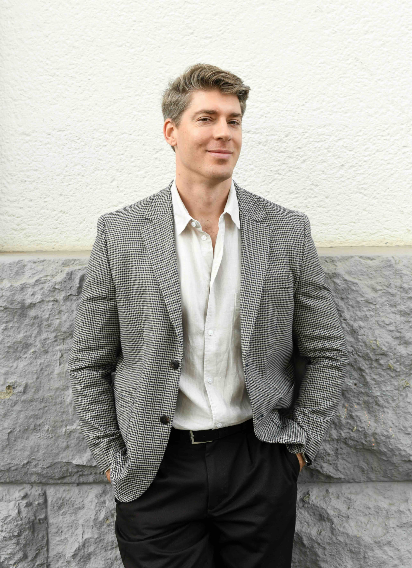 Nick Praulins standing against a pale stone wall in Stockholm
